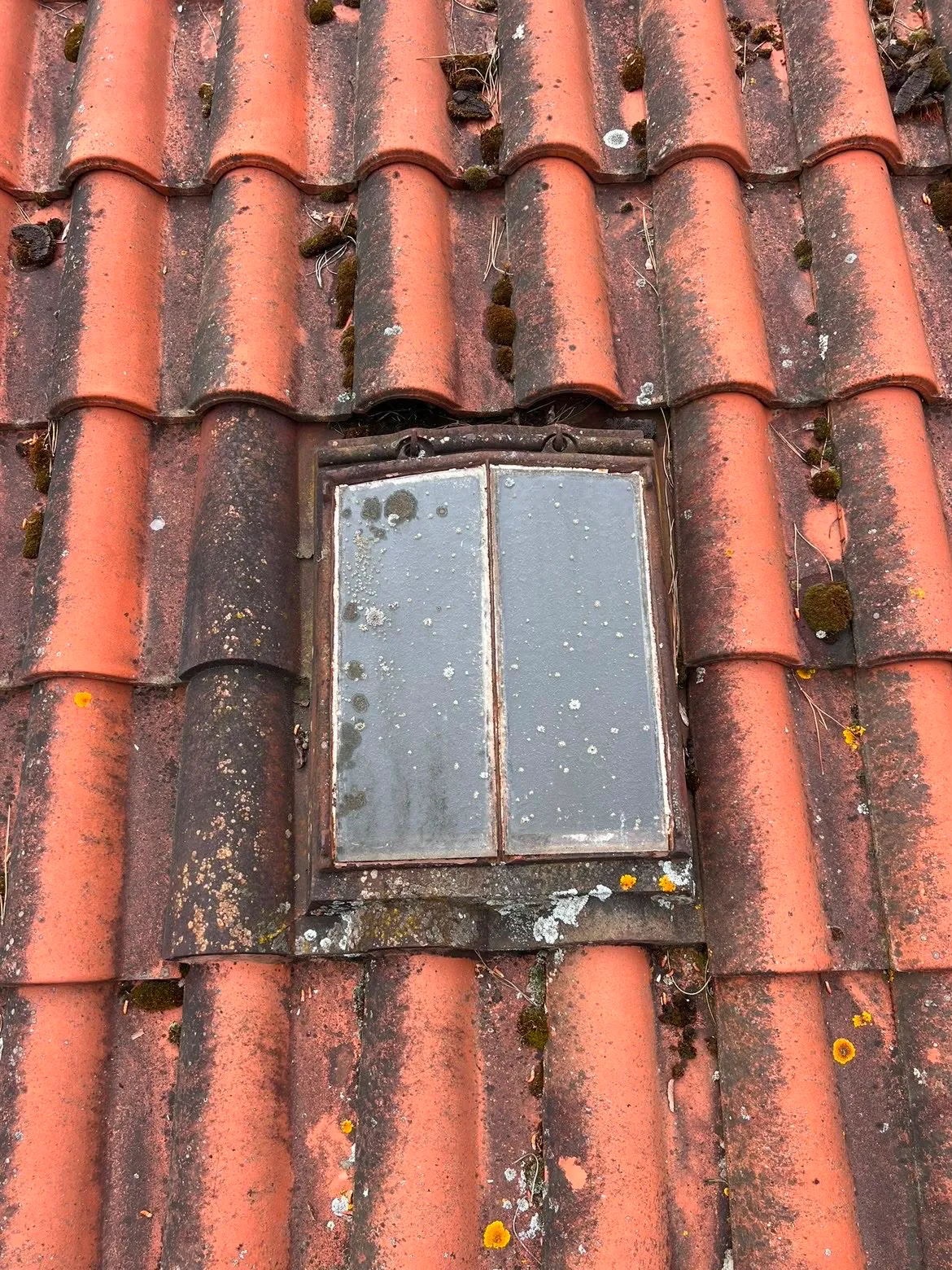 Ancienne fenêtre de toit en fonte à remplacer sur une couverture en tuile